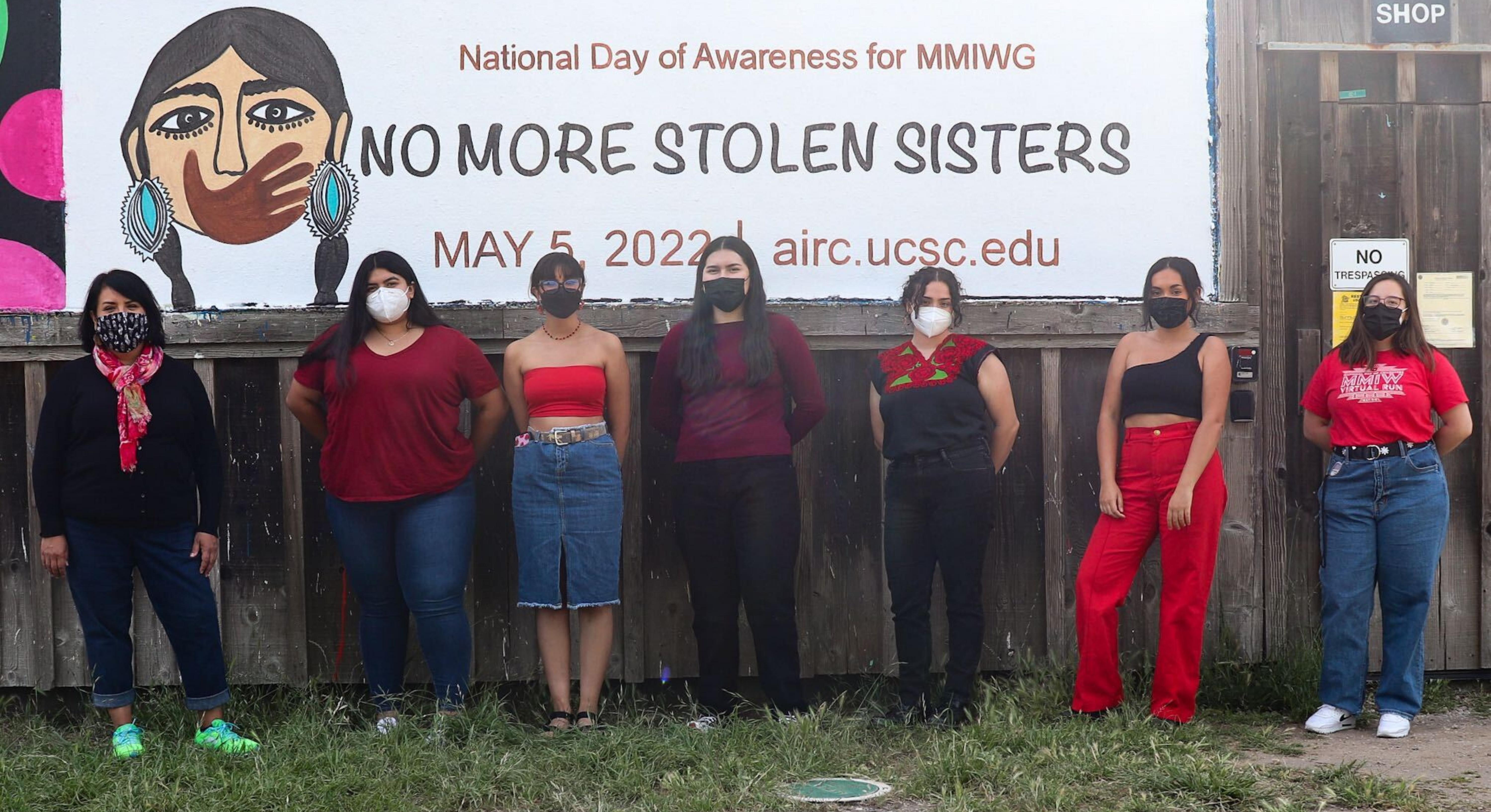 AIRC team posing in front of MMIWG banner painted at the base of UCSC campus, May 2022