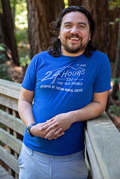Headshot photo of Frank smiling on a UCSC bridge wearing a blue shirt.